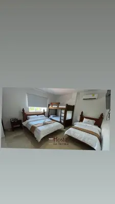 a bedroom with three beds and a tv at Hostal La Heroica in Cartagena de Indias