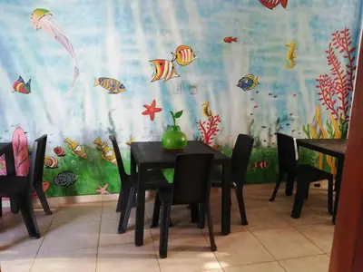 a dining room with a table and chairs with a fish mural at Hotel Brisas del Mar San Antero in San Antero