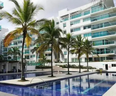 a swimming pool with palm trees in front of a building at Cartagena Boquilla Morros playa apt 1 in Cartagena de Indias