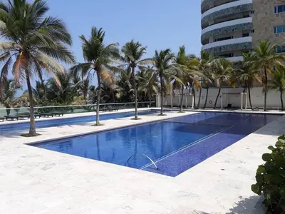 a swimming pool with palm trees and a building at APTO EN LA BOQUILLA CARTAGENA MORROS 922 in Cartagena de Indias
