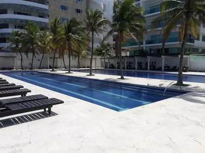 a swimming pool with palm trees next to a building at APTO EN LA BOQUILLA CARTAGENA MORROS 922 in Cartagena de Indias