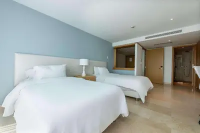 a bedroom with two white beds and a bathroom at Radisson Cartagena Ocean Pavillion Hotel in Cartagena de Indias