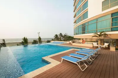 a swimming pool with lounge chairs next to a building at Radisson Cartagena Ocean Pavillion Hotel in Cartagena de Indias
