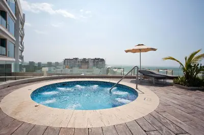 a swimming pool on top of a building with an umbrella at Bello apartamento dentro del Hotel Radisson Ocean Pavillion in Cartagena de Indias