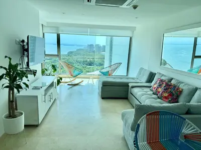 a living room with a couch and chairs and the ocean at Bello apartamento dentro del Hotel Radisson Ocean Pavillion in Cartagena de Indias