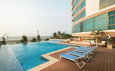 a swimming pool with lounge chairs next to a building at Bello apartamento dentro del Hotel Radisson Ocean Pavillion in Cartagena de Indias