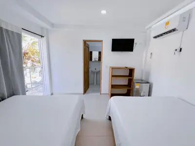two beds in a white room with a window at Condominio bahia blanca in Coveñas