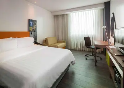 a hotel room with a large white bed and a desk at Hampton by Hilton Barranquilla in Barranquilla