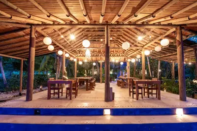 a wooden pavilion with tables and chairs and lights at Hotel Playa Manglares Isla Baru in Baru