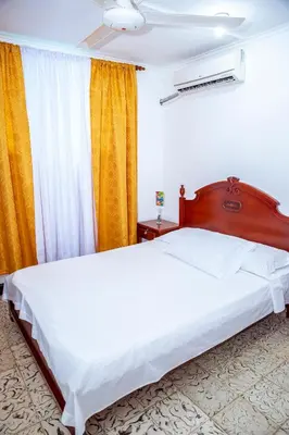 a bedroom with a large bed and a yellow curtain at Aqui me quedo in Cartagena de Indias
