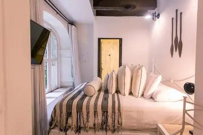 a bedroom with a bed with pillows and a television at Leones de Alba Hotel Boutique in Cartagena de Indias