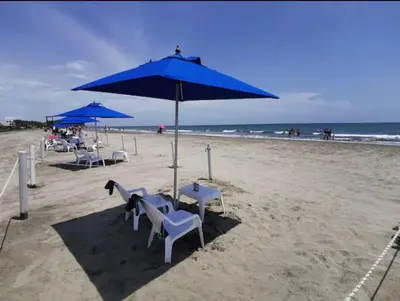 a beach with chairs and a blue umbrella on the sand at Apartamento en cartagena Boquilla vista al mar dos Hab in Cartagena de Indias