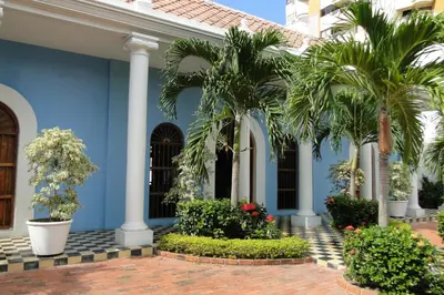 a blue building with palm trees in front of it at Casa Bustamante Hotel Boutique in Cartagena de Indias