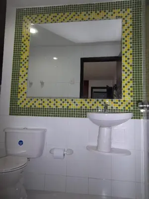 a bathroom with a sink and a toilet and a mirror at Hotel Golden House in Barranquilla