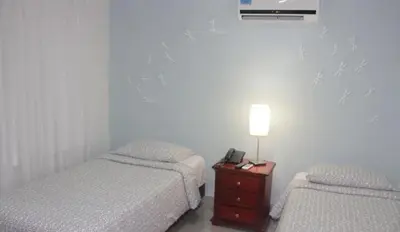 a bedroom with two beds and a table with a lamp at Hotel Golden House in Barranquilla