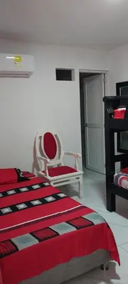 a bedroom with a red bed and a chair at LA MEDELLIN HOSTAL in Cartagena de Indias