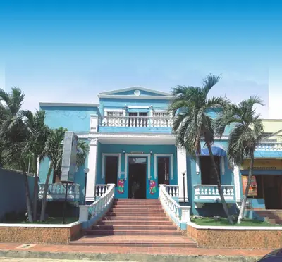 a blue house with palm trees in front of it at Hotel Del Mar Inn in Barranquilla