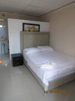 a bedroom with a large bed with white sheets at Hotel Del Mar Inn in Barranquilla