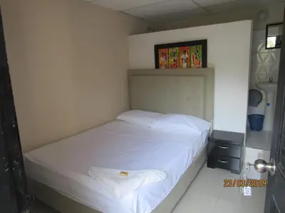 a small bedroom with a bed with white sheets at Hotel Del Mar Inn in Barranquilla