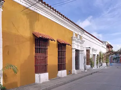 a yellow building with barred windows on a street at Casa Digna in Cartagena de Indias