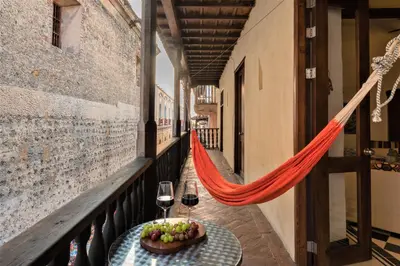 a table with a bowl of fruit and wine glasses on a balcony at Casa San Pedro - Exclusive 3BR Colonial Apt in Centro Historico by Huespedia in Cartagena de Indias