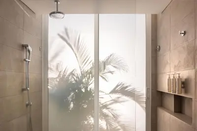 a bathroom with a glass door with a palm tree reflection at Santa Marta Marriott Resort Playa Dormida in Santa Marta