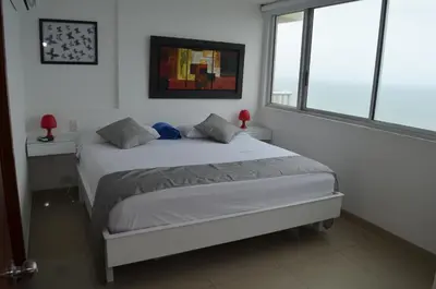 a bedroom with a white bed with two windows at palmetto frente al mar in Cartagena de Indias