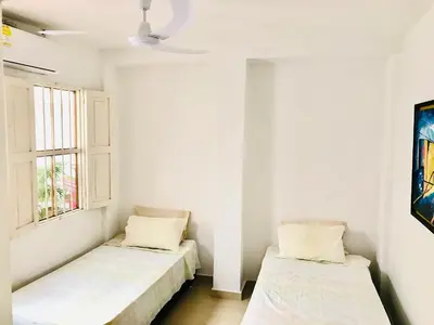 two beds in a white room with a window at Calle de la iglesia 35-59 in Cartagena de Indias
