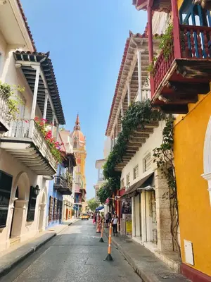 an empty city street with buildings and flowers on balconies at Calle de la iglesia 35-59 in Cartagena de Indias