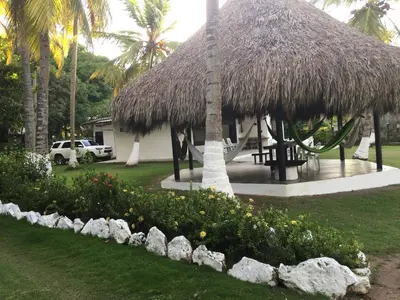 a resort with a straw hut and a garden with flowers at Cabaña La Niña Cande-Punta Bolivar in San Antero