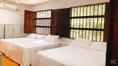 two beds in a room with two windows at Cabaña La Niña Cande-Punta Bolivar in San Antero