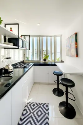 a white kitchen with two stools and a counter at Alojamiento con Vista Y Salida al Mar in Cartagena de Indias