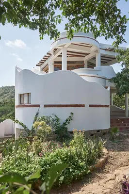 a house shaped like a whale sits in a garden at Casa Caracola in Tubará