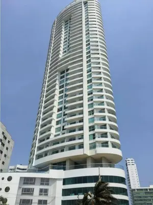 a tall building with a palm tree in front of it at Encantador apartamento frente a la playa in Cartagena de Indias