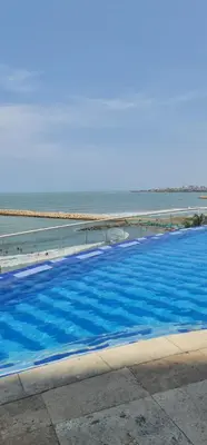 a large blue swimming pool next to the ocean at Encantador apartamento frente a la playa in Cartagena de Indias
