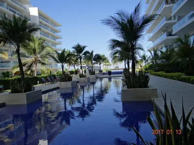 a swimming pool with palm trees in front of a building at Apartamento en Cartagena primera linea de Playa Morros Epic in Cartagena de Indias