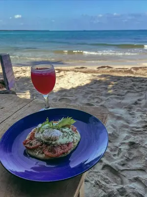 a plate of food and a drink on the beach at Canto de Caracola in Rincón