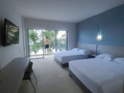 a bedroom with two beds and a man walking out the window at Hotel Rilux Tolú -Casa Danae- in Tolú