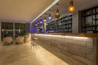 a bar with a stone wall and chairs and lights at Grand Sirenis Cartagena in Cartagena de Indias