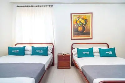 two beds with blue pillows in a room with a window at Ayenda 1309 Villa Dilia in Barranquilla