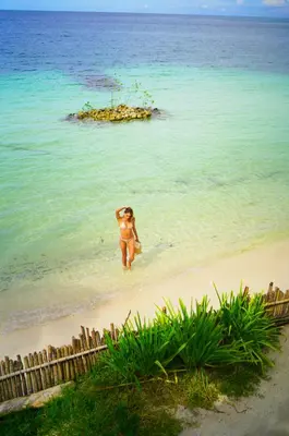 a woman walking in the water on a beach at Casa Tinti in Tintipan Island