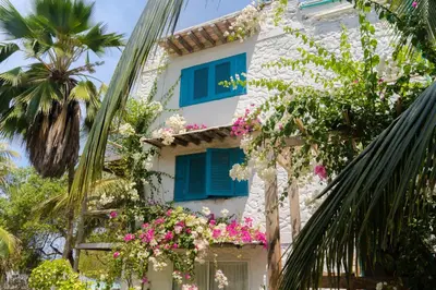 a building with blue shutters and flowers on it at Casa Tinti in Tintipan Island