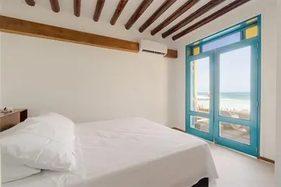a bedroom with a bed and a window with the beach at Casa Tinti in Tintipan Island