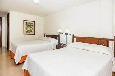 two beds in a hotel room with white sheets at Hotel Majestic in Barranquilla