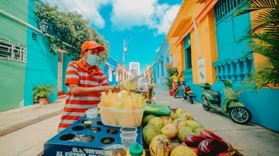 a man wearing a mask standing next to a fruit stand at Casa Amanzi Cartagena by Bernalo Hotels in Cartagena de Indias