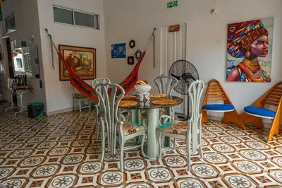 a dining room with a table and chairs and a painting at Hostal Badillo SV in Cartagena de Indias