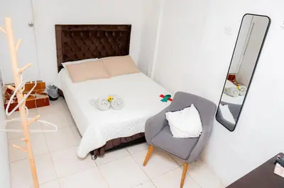 a small bedroom with a bed and a chair at Hostal Badillo SV in Cartagena de Indias