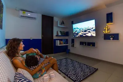 a woman and a child sitting on a couch watching tv at Casa del Puerto Hostel & Suites in Cartagena de Indias