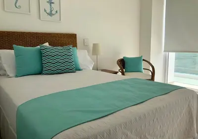 a bedroom with a large bed with blue and white pillows at Marina Puerto Velero in Tubará