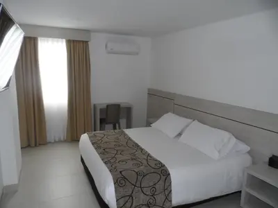 a bedroom with a large white bed and a window at Hotel Arawak Plaza in Sincelejo